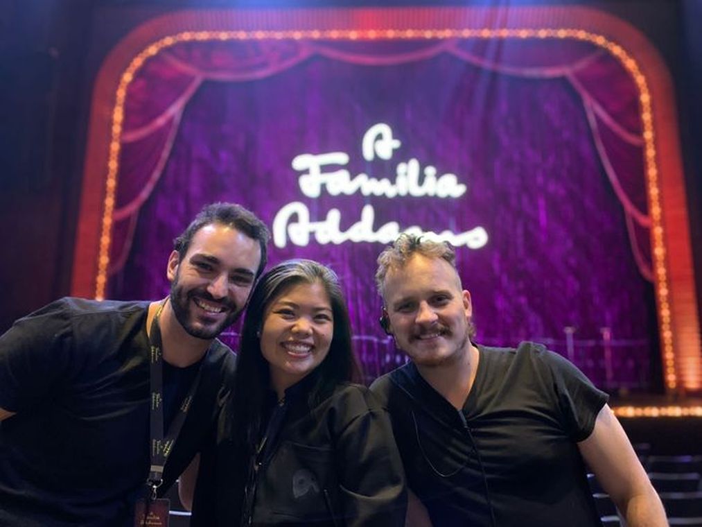 Camila Chiba, Luciano Fernandes e Flávio Bregantin diante do letreiro de A Família Addams