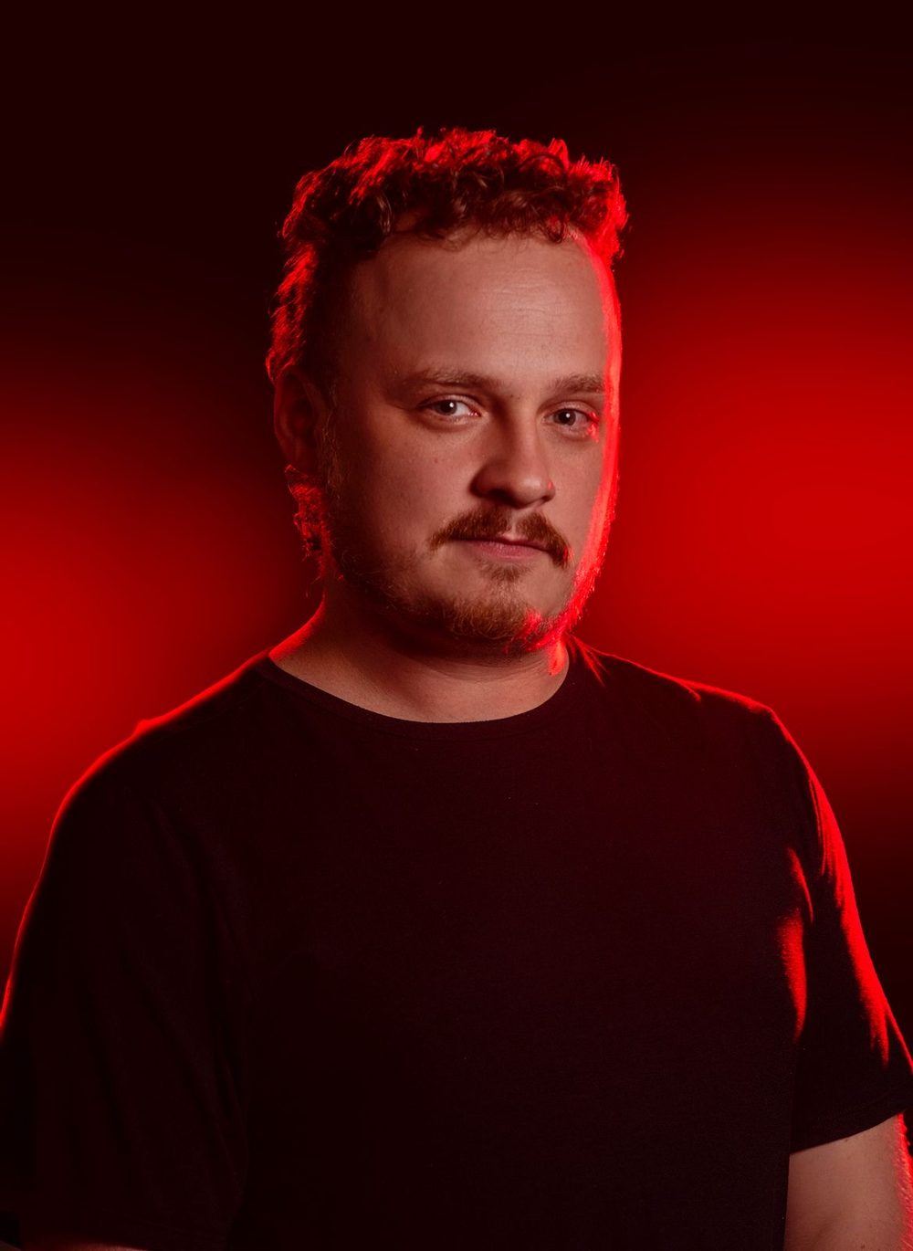 Retrato de Flávio Bregantin, Stage Manager de teatro musical, em luz vermelha de palco